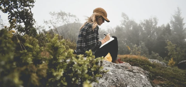 femme qui écrit dans un carnet en nature, pour illustrer le carnet des curiosités